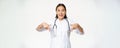 Enthusiastic medical staff, asian female healthcare worker, pointing fingers down and smiling amazed, showing discounts Royalty Free Stock Photo