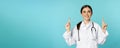 Enthusiastic medical worker, young woman doctor in white coat, stethoscope, showing advertisement, pointing fingers up