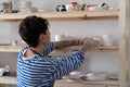 Enthusiastic pensive woman opens own store with natural clay dishes displaying goods on wall shelves Royalty Free Stock Photo