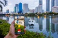 Enthusiastic Pokemon player is catching Pikachu at waterside in the Benchakiti Park Royalty Free Stock Photo