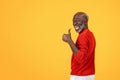 Enthusiastic senior Black man with a white beard giving a thumbs up sign, turning back with a big smile