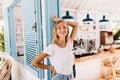 Enthusiastic slim girl in jeans posing with pleasure in cafeteria. Portrait of fashionable blonde t