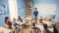 Enthusiastic Teacher Explaining Lesson to a Classroom Full of Diverse Bright Children, In Elementa Royalty Free Stock Photo