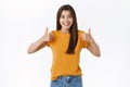 Enthusiastic, thrilled young woman think your idea awesome, rate good movie, showing thumbs-up smiling happy and giving