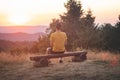 Enthusiastic traveler sits on a wooden bench and watches the last remnants of sunshine in the raw nature. Sunset on Horni Becva,