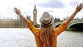 Enthusiastic traveler student girl with raised arms in London enjoying the view of mains attractions, UK