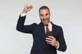 Enthusiastic young man in elegant suit holding fist above head and cheering