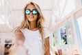 Enthusiastic young woman fooling around in cafeteria. Lovely tanned girl in sunglasses posing emoti