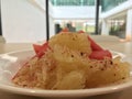 A white plate, Thai fruits, pomelo topped with chilli, salt and sugar, comes with juicy watermelon.