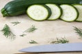 Entire raw zucchini and several pieces with fennel and knife on wooden background Royalty Free Stock Photo