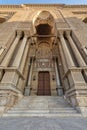 Entrance of al Rifai Mosque with closed decorated wooden door, ornate columns, ornate recessed stone wall and stairs, Cairo, Egypt