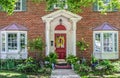 Entrance with columns and bay windows of beautiful two-story brick house with pots of flowers and yellow climbing roses and Royalty Free Stock Photo
