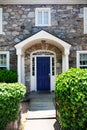 Entrance door to a large stone house with columns. Blue door and green shrub at the entrance Royalty Free Stock Photo