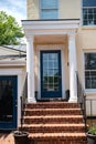 Entrance door to a large stone house with a porch and columns. Glass door, window and stone steps Royalty Free Stock Photo