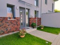 Entrance door to modern house with beautiful potted plants, bushes and green grass