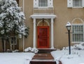 Entrance of elegant upscale stucco house with pillars and tiles in snow with bright red door Royalty Free Stock Photo