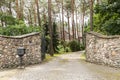 Entrance gate to a rustic, english house in the forest with stone wall and cobblestone driveway