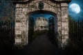 Entrance gateway to an old abandoned Victorian mansion house under a moonlit sky at night. 3D rendering Royalty Free Stock Photo