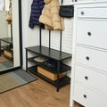 An entrance hall with a hanger and a chest of drawers in a home apartment. Shoes on shelves and jackets on hangers in the hallway