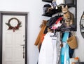 An entrance hall with outerwear on a hanger, a pet cat sitting in a basket on a shelf for hats. Mess in the hall. The front door Royalty Free Stock Photo