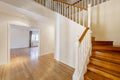 Entrance hall of a two-storey detached house with a wooden staircase and a white balustrade Royalty Free Stock Photo
