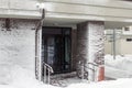 Entrance of modern high-rise apartment building covered with snow and frost after heavy windy snowstorm Snowfall and blizzard Royalty Free Stock Photo