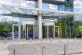 Entrance of modern office building exterior with blue sky and green trees reflections glass windows background Royalty Free Stock Photo