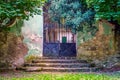 Entrance in an old mansion with stairs full of leaves and a rusty fence Royalty Free Stock Photo