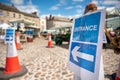 Entrance sign and orange traffic cones on cobblestones at restricted entrance to outdoor market stalls