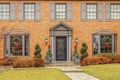 Entrance of stately upscale brick home with bay windows and grayish trim decorated for Christmas Royalty Free Stock Photo