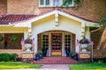 Entrance and stuco bungalow porch with french doors and tile roof on brick house with many flower pots and American flags and star Royalty Free Stock Photo