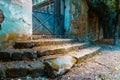 Entrance to an abandoned house with a rusty blue gate. Out of focus stairs in the foreground Royalty Free Stock Photo