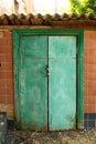 The entrance to the basement is locked. Green old door closed on the padlock