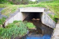The entrance to the concrete collector for the river, stream with grass, sand and granite stones on the sides. Hydraulic