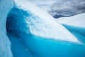 Entrance to dark ice cave flooded by deep blue water on the Matanuska Glacier in Alaska