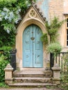 Entrance to a historic manor, framed by antique architectural elements and flanked by potted topiaries, features an aged door