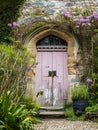 Entrance to a historic manor, framed by antique architectural elements and flanked by potted topiaries, features an aged door