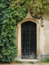 Entrance to a historic manor, framed by antique architectural elements and flanked by potted topiaries, features an aged door