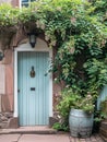 Entrance to a historic manor, framed by antique architectural elements and flanked by potted topiaries, features an aged door