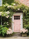 Entrance to a historic manor, framed by antique architectural elements and flanked by potted topiaries, features an aged door