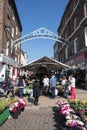 Entrance to the historic Shambles Market showing entrance sign, buildings, people and flower maket stall