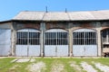 Entrance to large old train station repair workshop with overgrown train tracks leading to front doors Royalty Free Stock Photo