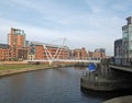 the entrance to leeds dock on the river aire with pedestrians crossing knights bridge and the royal armouries building visible Royalty Free Stock Photo