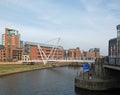 the entrance to leeds dock on the river aire with pedestrians crossing knights bridge and the royal armouries building visible