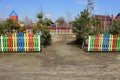 Entrance to the playground with green pines and colored wooden decorative fence Royalty Free Stock Photo