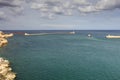 Entrance to the Valletta city harbor at Malta, with many historic buildings along the coastline and guarded by two lighthouses