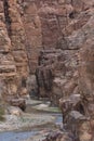 Entrance to the Wadi Mujib canyon in Jordan. Steep rocks and a rapid flowing river carved. Difficult crossing and attraction for Royalty Free Stock Photo