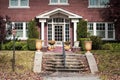 Entrance of two story upscale brick house in autumn with steps and pole laturn and pillared porch with attractive paned front door Royalty Free Stock Photo