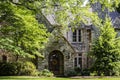 Entrance of upscale multi-gabled rock house with arched porch and front door with wreath and lush foliage and landscaping Royalty Free Stock Photo