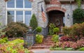 Entrance and window to beautiful rock upscale house with lush landscaping and American flag and wreath on door Royalty Free Stock Photo